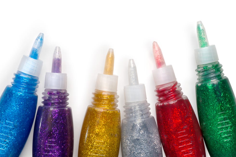 Set of colored glitter glue tubes on white with path