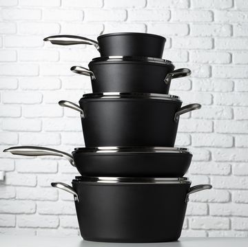 set of cookware on table against white brick wall