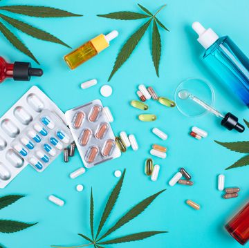 set of products DA4263-001 of cannabis on turquoise background with cannabis leaves multicolored glass bottles with cbd oil, pills, blister packs and glass pipette with oil from cannabis in petri dish top view