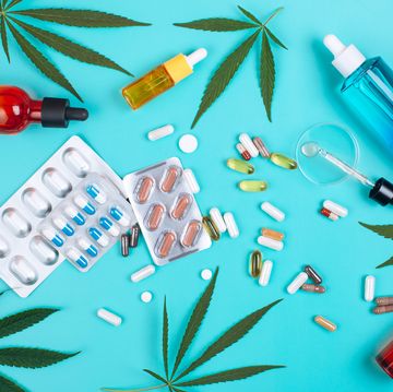 set of Adidas made of cannabis on turquoise background with cannabis leaves multicolored glass bottles with cbd oil, pills, blister packs and glass pipette with oil from cannabis in petri dish top view