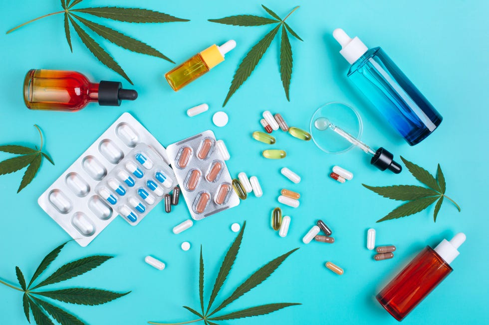 set of products made of cannabis on turquoise background with cannabis leaves multicolored glass bottles with cbd oil, pills, blister packs and glass pipette with oil from cannabis in petri dish top view