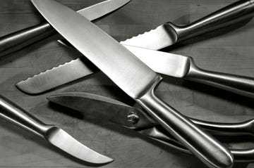 set of stainless steel knives arranged on wooden cutting board