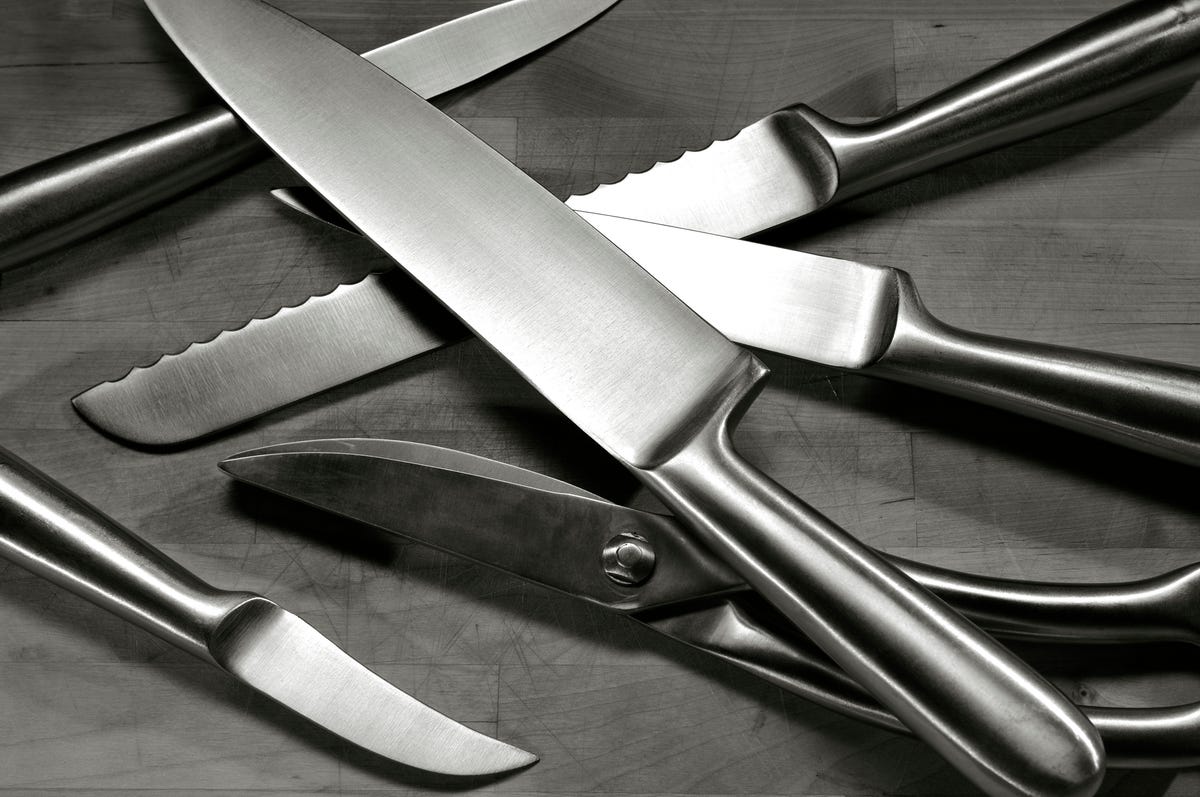 set of stainless steel knives arranged on wooden cutting board