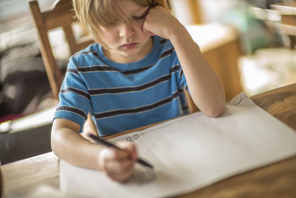 Seven year old boy drawing at the table