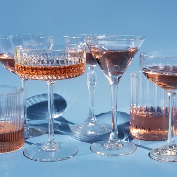 several cocktail or mocktail glasses with rose wine drink on blue