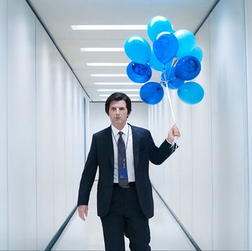 man in a suit holding blue balloons while walking in a modern hallway man in a suit holding blue balloons while walking in a modern hallway