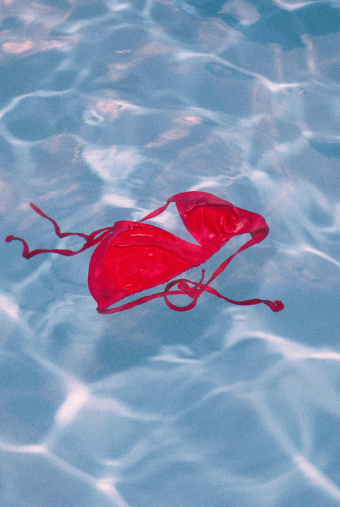 red bikini top floating in a blue pool