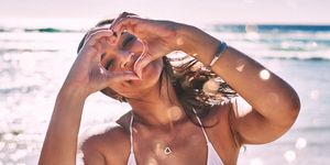 portrait of a beautiful young woman making a heart shaped gesture with her hands at the beach