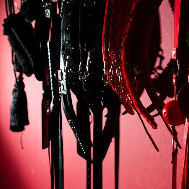 sex toys hanging on red wall in store