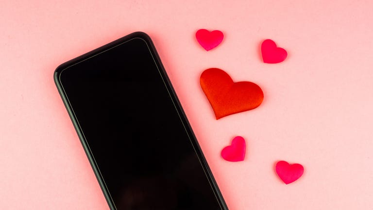 Mobile phone and red hearts on a pink background