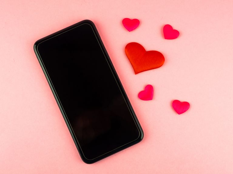 Mobile phone and red hearts on a pink background