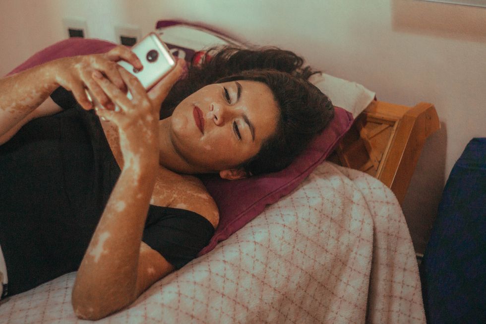Girl lies on her bed texting on her phone
