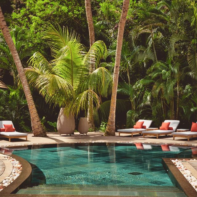 a pool with lounge chairs and palm trees around it