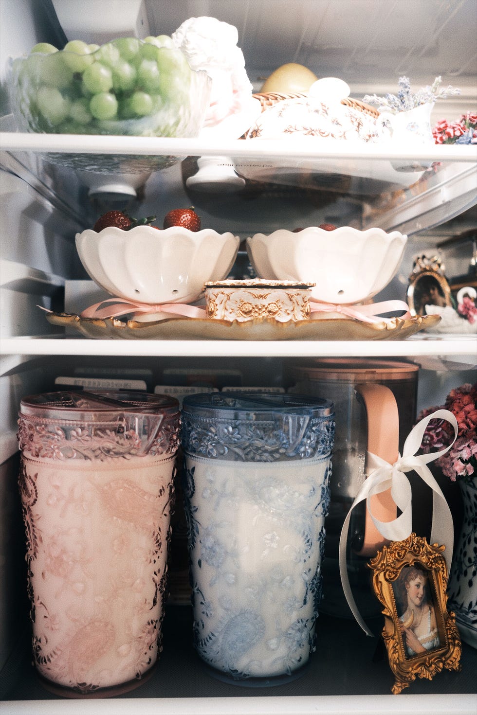 a close-up of the fridge interior with matching ceramic bowls, pretty white bows and a framed vintage photo