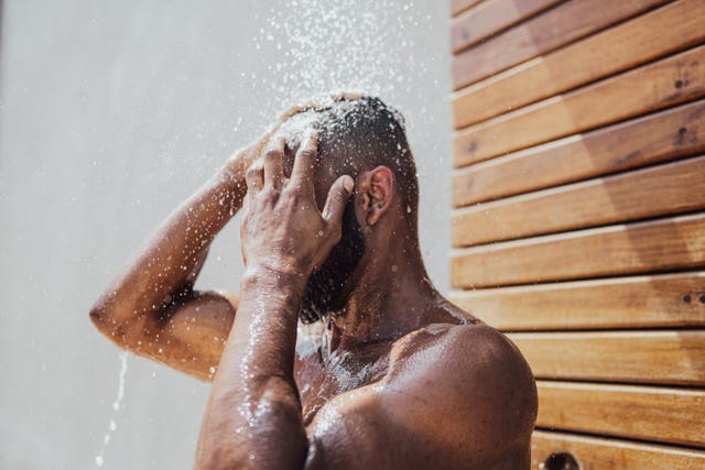 mid adult man taking a shower outdoors