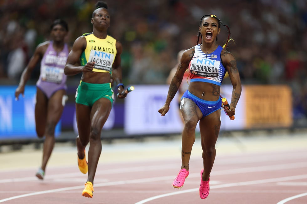 shacarri richardson celebrating on a track while holding a baton in her left hand