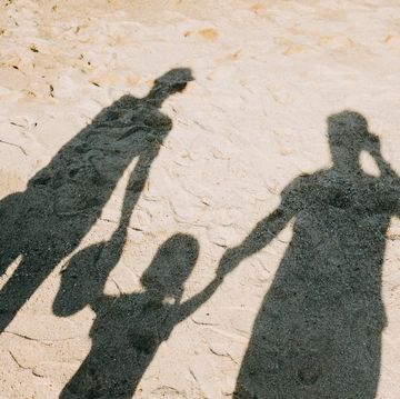 shadow on sandy beach of a loving family of three holding hands relaxing on a lovely sunny day