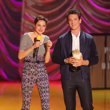 shailene woodley and miles teller at an awards show, both smiling as miles holds an award shaped like a popcorn bowl