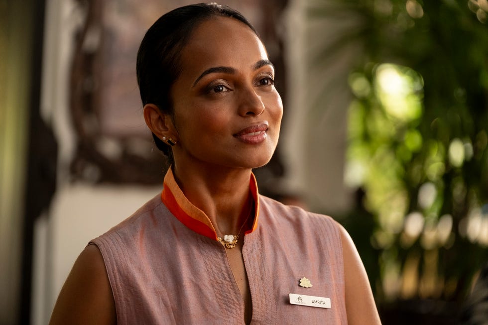 a staff member wearing a name tag and traditional attire stands in a welcoming pose