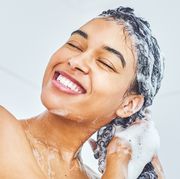 woman sudsing shampoo in hair in shower