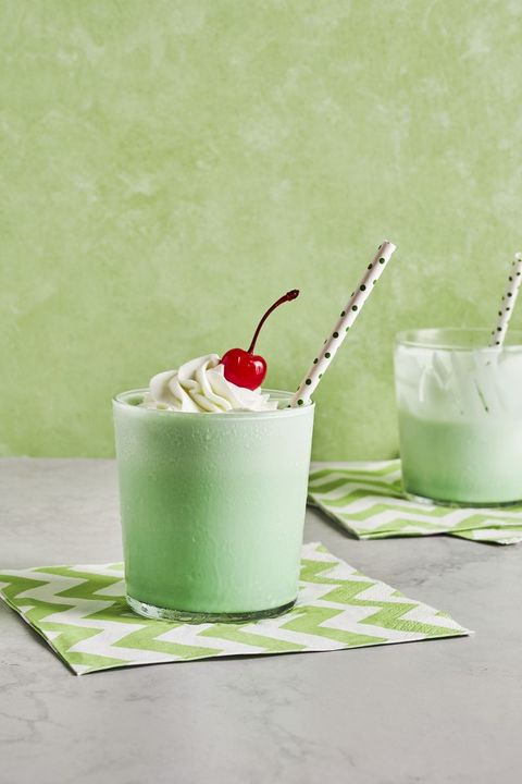 copycat shamrock shake topped with whipped cream and a maraschino in a glass with a polka dot paper straw
