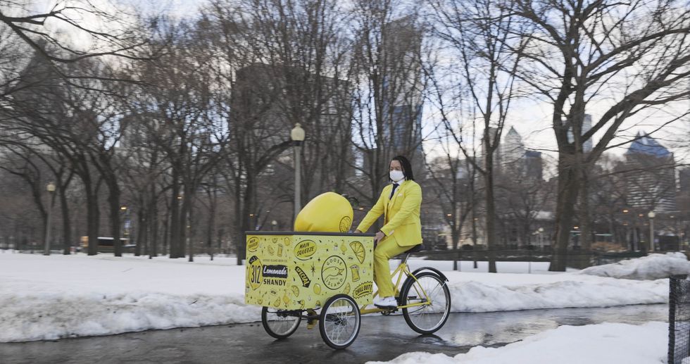 the shandy man riding a cargo bike holding a giant lemon in a chicago park