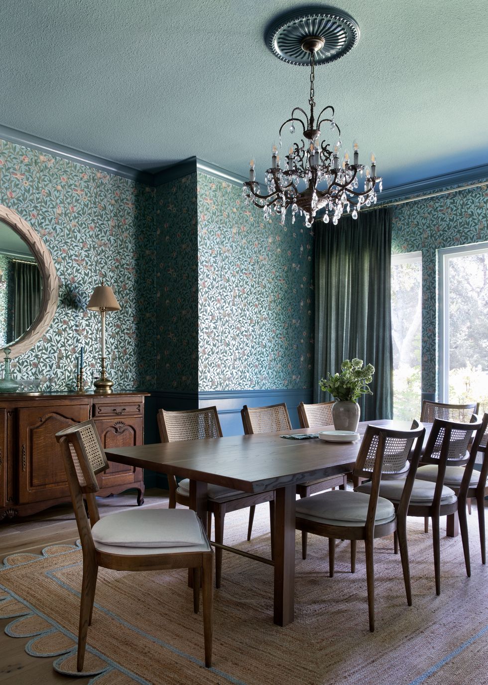 dining room with long table, chandelier, and teal wallpaper