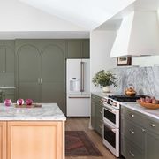 kitchen, olive green cabinets, wooden island with marble countertop, white oven, white range hood
