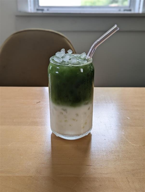layered beverage in a glass with ice and a straw