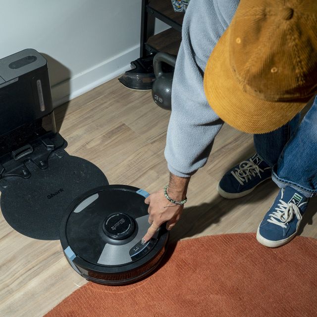 man pressing clean button on shark 2 in 1 robot vacuum and mop