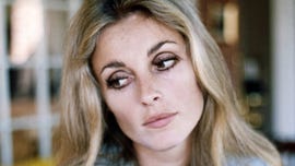 sharon tate looks down and to the left of the camera, she has on heavy eye makeup and her long blonde hair is down
