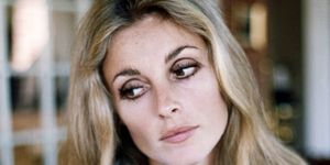 sharon tate looks down and to the left of the camera, she has on heavy eye makeup and her long blonde hair is down
