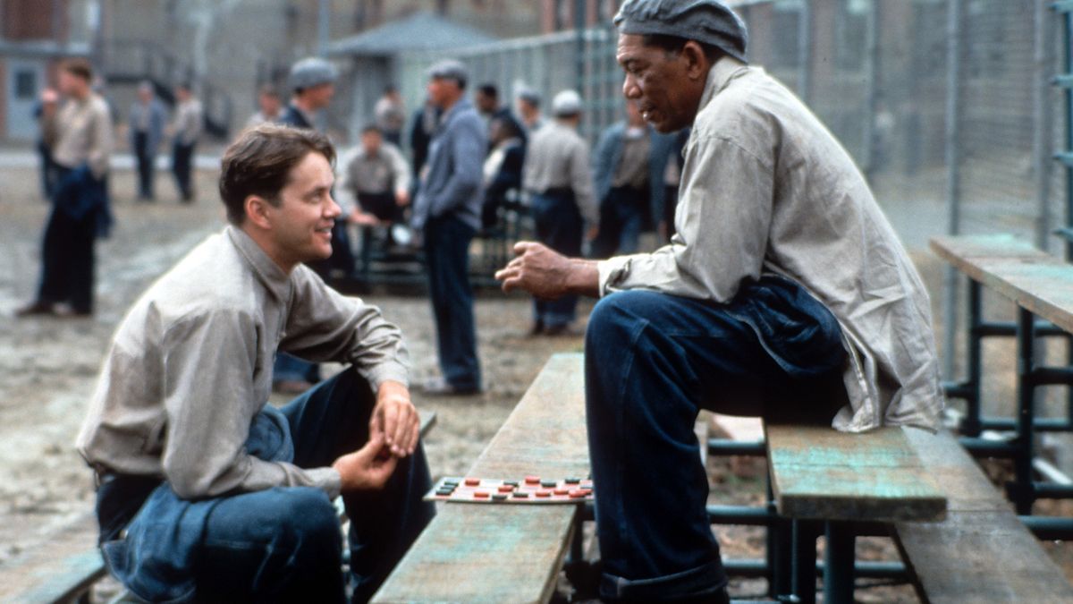 Tim Robbins and Morgan Freeman sitting outside on the benches playing checkers and talking in a scene from the film 'The Shawshank Redemption', 1994. (Photo by Castle Rock Entertainment/Getty Images)