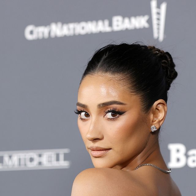 shay mitchell at the baby2baby gala on the red carpet with her hair up and wearing a black off the shoulder gown