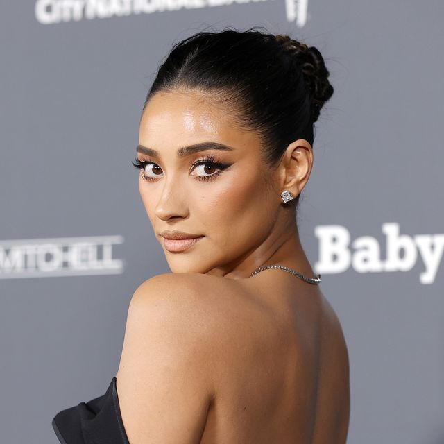 shay mitchell at the baby2baby gala on the red carpet with her hair up and wearing a black off the shoulder gown