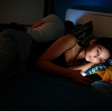 she is checking her smartphone at bedtime