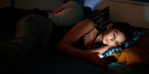 she is checking her smartphone at bedtime