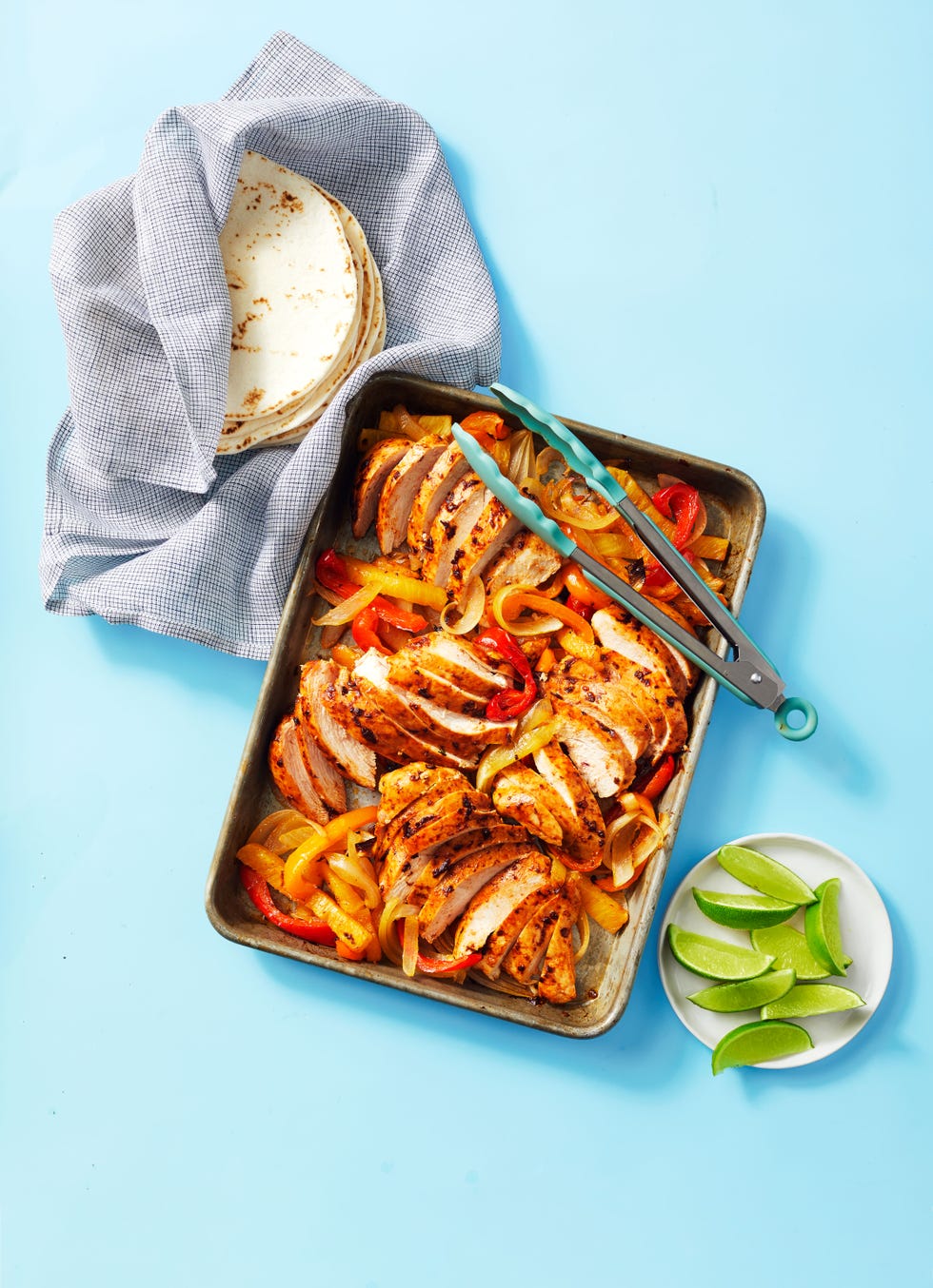 sheet pan chicken fajitas on a sheet pan with a side of lime slices