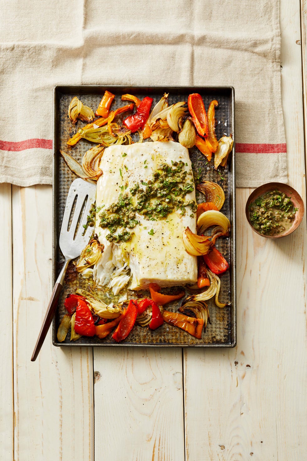 fish and vegetables on a sheet pan with a spatula