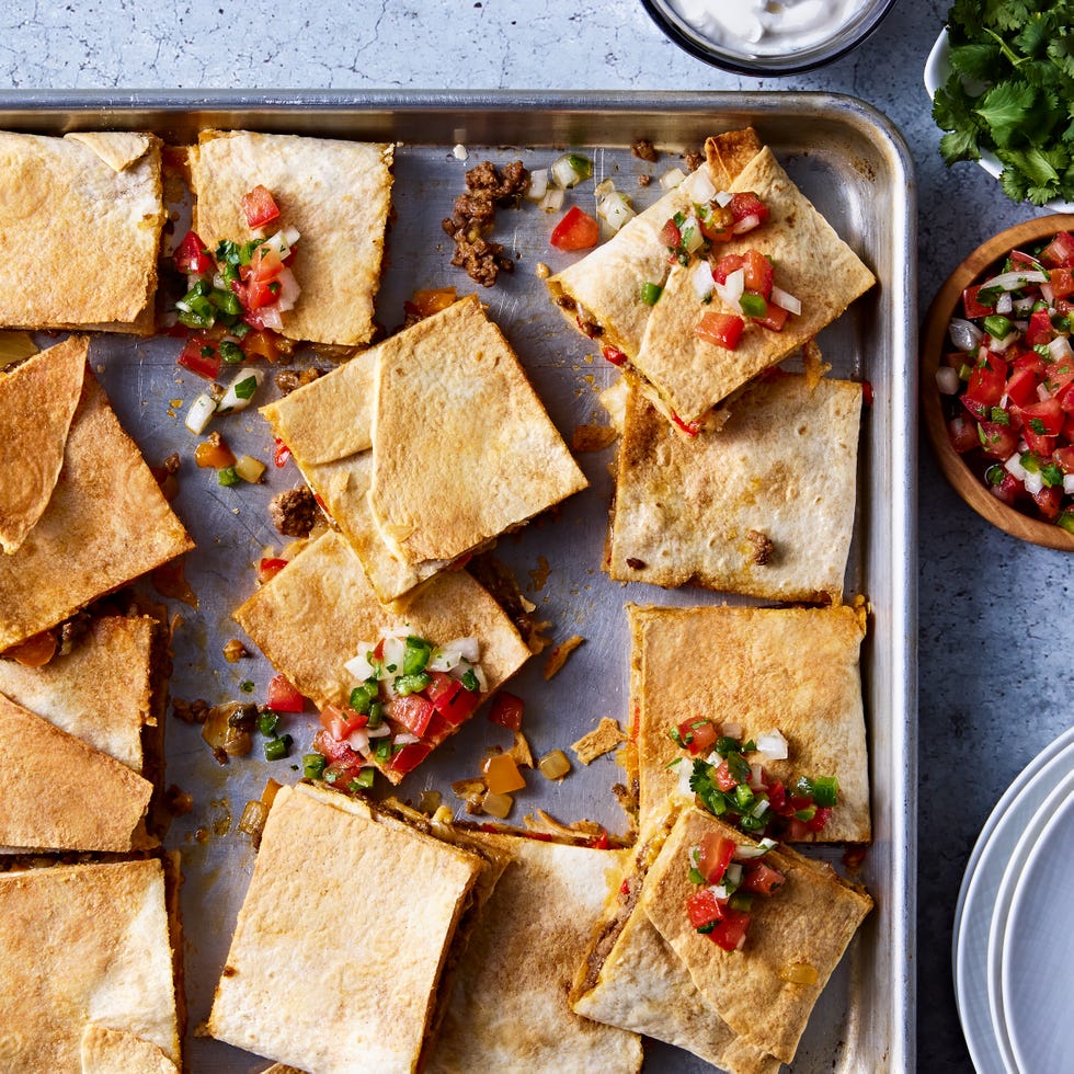 tortillas filled with meat and cheese on a sheet pan