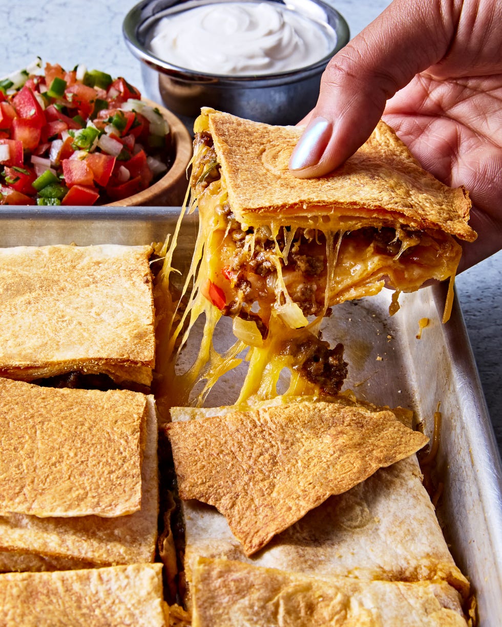 tortillas filled with meat and cheese on a sheet pan