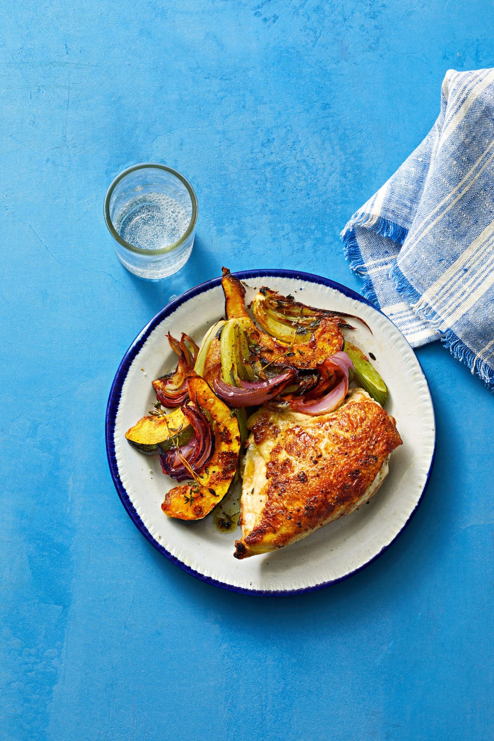 chicken on a plate with a roasted vegetables on the side