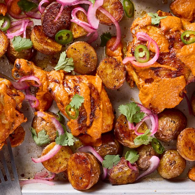 chicken thighs covered in a tikka masala sauce with pickled red onions and jalapenos on a sheet pan