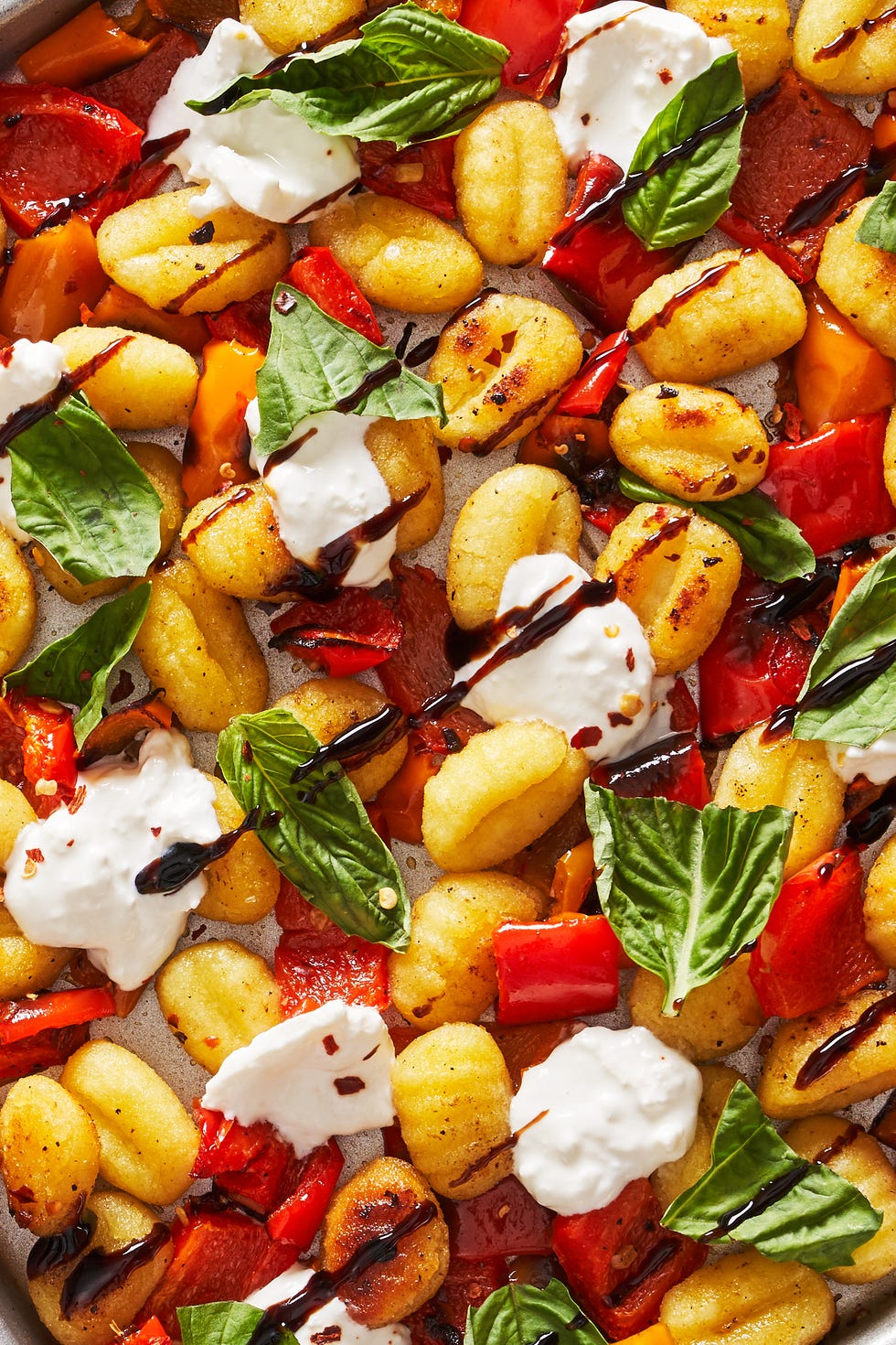 sheet pan roasted gnocchi and peppers topped with burrata, basil and balsamic reduction
