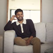 jay shetty sitting on a sofa in front of a window