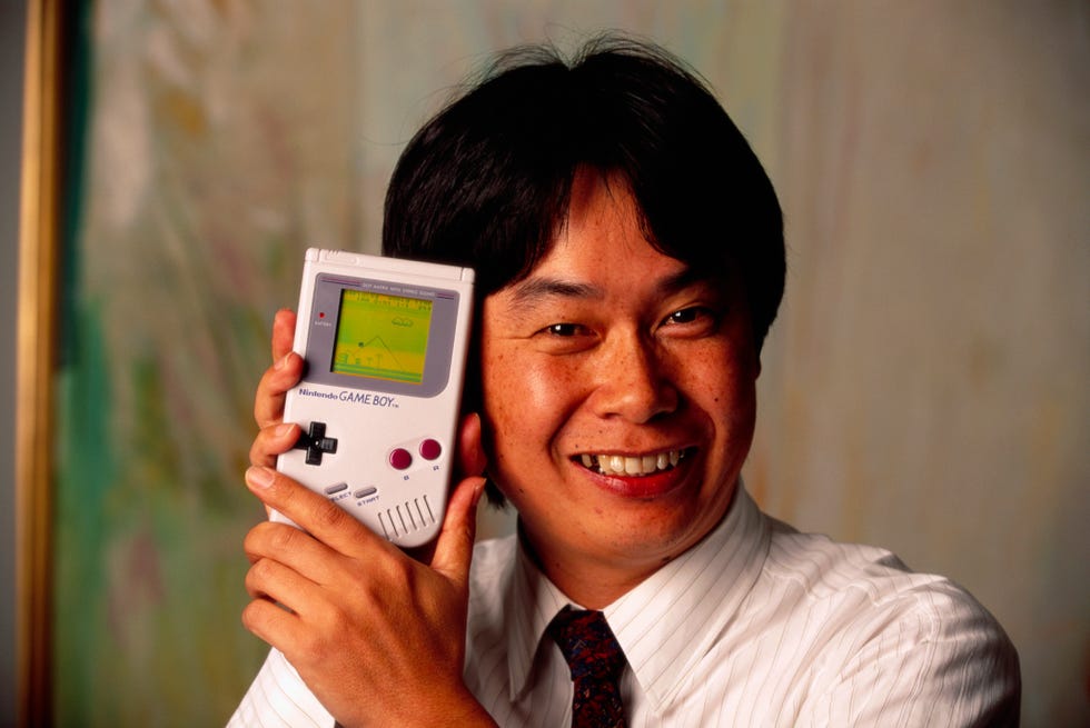 shigeru miyamoto holding a nintendo game boy