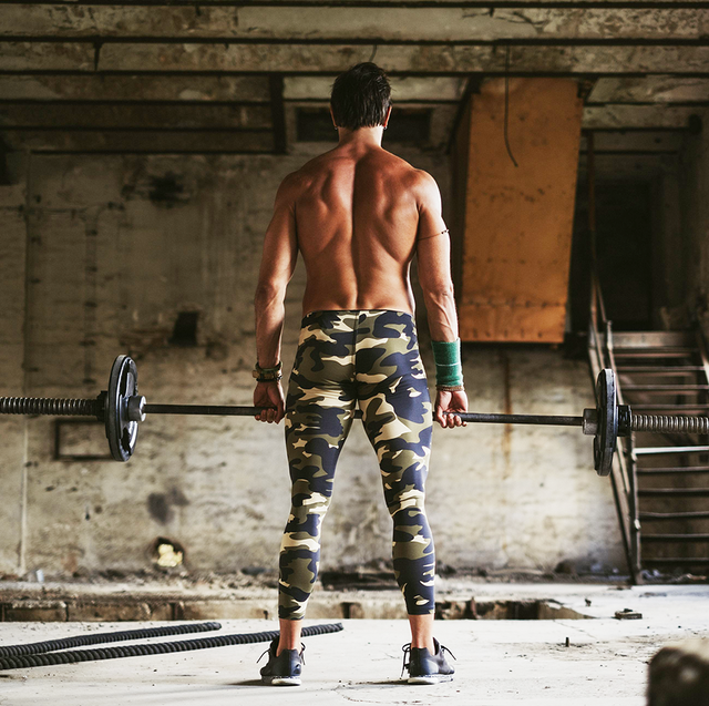 Shirtless man deadlifts in deserted building