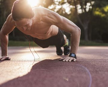 shirtless man exercing push ups on sport field