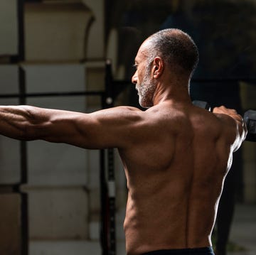 shirtless man holding dumbbells in gym