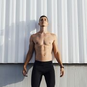 shirtless man standing against wall outdoors